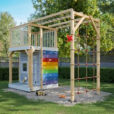 an outdoor play structure made out of pallet boards and wooden slats with a rainbow painted roof