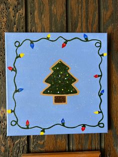 a christmas tree is painted on a blue canvas