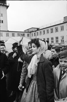 black and white photograph of woman holding an umbrella in front of people on the street