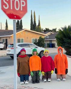 four children in costumes standing under a stop sign