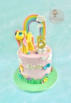 a pink cake with a pony and rainbow on top