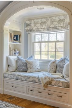 a window seat with pillows on it in front of a bookcase and bookshelf