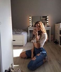 a woman sitting on the floor taking a selfie