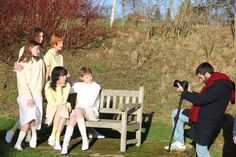 a group of people sitting on top of a wooden bench next to a park bench