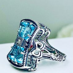 Indulge in the whimsical allure of our vintage-inspired Versailles/Baroque ring, a captivating piece that seamlessly blends elegance with intricate detailing.

At its heart, four tapered baguette gems delicately converge, forming a radiant center adorned with a silver bow, embellished by a dazzling CZ stone—an enchanting focal point that captivates the eye. Elegant Silver Jeweled Ring, Blue Jeweled Rings For Gifts, Silver Jeweled Ring For Anniversary, Blue Jeweled Rings For Gift, Vintage Sapphire Rings With Diamond Accents, Vintage Jeweled Rings, Vintage Ring With Gemstone Accents As A Gift, Unique Jeweled Anniversary Ring, Vintage Wedding Rings With Gemstone Accents