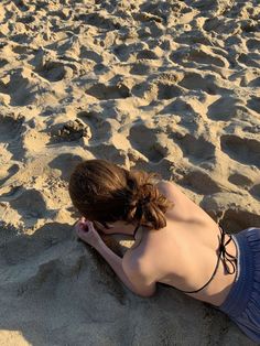 a woman laying on top of a sandy beach