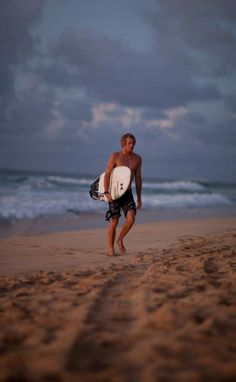 a man walking on the beach with a surfboard