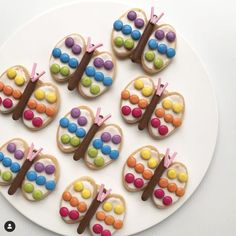 decorated cookies are arranged on a plate with chocolate and candy decorations in the shape of butterflies