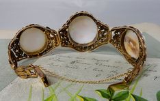 "Here's an antique carved shell cameo bracelet, set in 10k gold. It features 3 cameos, the middle one being larger than the two on the sides. The setting has a delicate openwork construction of leaves, mounted onto a wire backing. The center link is 1.1/2\" wide, and the two sides are 1.1/4\". It has a hidden box clasp and safety chain, and is stamped, '10k' on the back of the clasp. Interior circumference is 7\". Completely original with no repairs and no damage. Thanks for looking." Antique 14k Gold Bracelet, Yellow Gold Cabochon Bracelets For Weddings, Antique Cabochon Bracelets For Wedding, Antique White Bracelet Jewelry, White Antique Bracelet Jewelry, Victorian Cameo Jewelry For Formal Occasions, White Antique Bracelet, Oval Cabochon Bracelet For Wedding, Oval Cabochon Wedding Bracelet