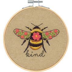 a cross stitch bee with the word kind on it's back and flowers in its wings