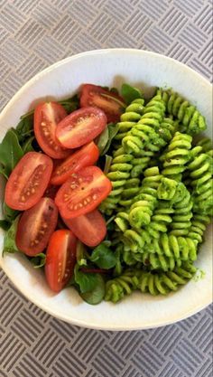 a white bowl filled with lots of green and red vegetables on top of a table