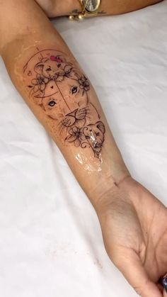 a woman's arm with a tattoo on it that has a cat and flowers on it