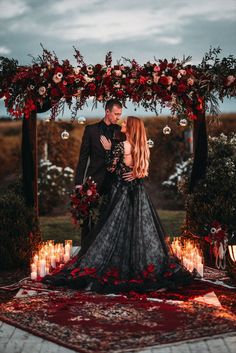 a man and woman standing under an arch with candles