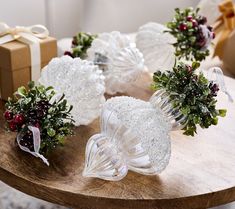 some glass ornaments are sitting on a table with presents in the background and one is empty