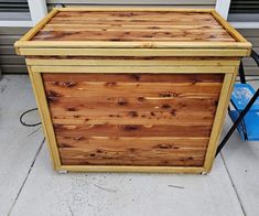 a large wooden box sitting on the side of a building next to a blue trash can