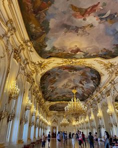 an ornately decorated room with chandeliers and paintings on the ceiling, along with red carpeting