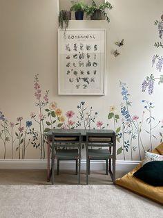 a living room with flowers painted on the wall and two chairs in front of it