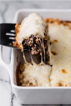 a close up of a piece of lasagna being lifted from a casserole dish