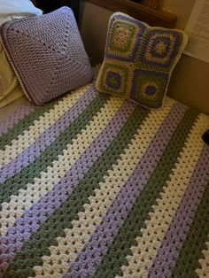 a crocheted blanket and two pillows on a bed