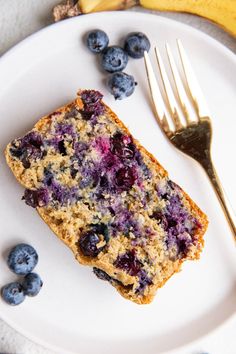 a white plate topped with blueberry muffins next to a fork and banana