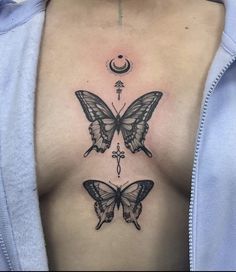 a woman's chest with two butterflies and a crescent tattoo on the left side