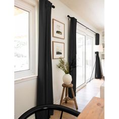 a living room filled with furniture and a window covered in black drapes next to a wooden table