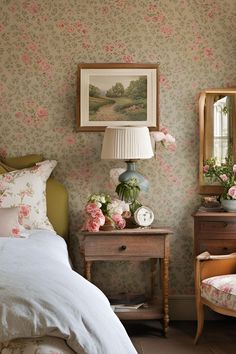 a bedroom with floral wallpaper and pink flowers on the bed, nightstands and mirror