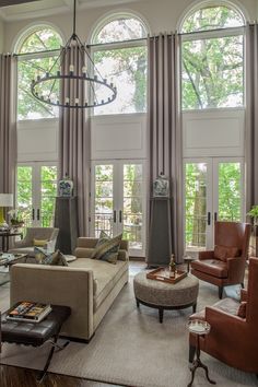 a living room filled with lots of furniture and large window covered windows over the top of them