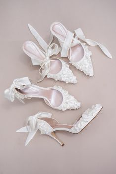 four pairs of white shoes with bows on the toes and one pair of high heeled shoes