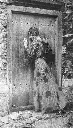 an old photo of a woman standing in front of a door with her hands up