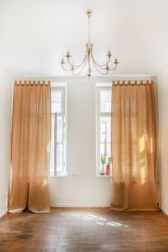 an empty room with two windows and a chandelier