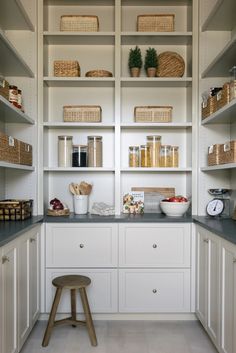 a kitchen with white cabinets and shelves filled with baskets, food items, and other things