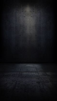 an empty dark room with light coming from the ceiling and concrete floor to the left