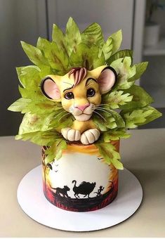 a lion figurine sitting on top of a cake covered in leaves and foliage