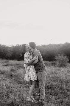 a man and woman kissing in an open field