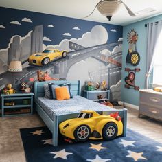 a child's bedroom decorated in blue and yellow with cars painted on the wall