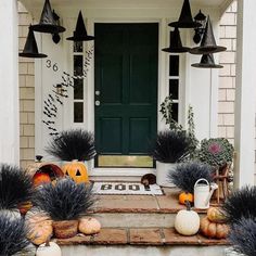 a front porch decorated for halloween with black and white pumpkins, witch hats and other decorations