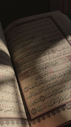 an open book with arabic calligraphy on it's pages and the sun shining through