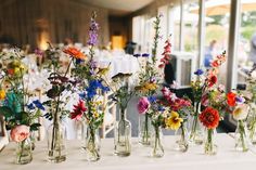 there are many vases that have flowers in them on the table at this wedding