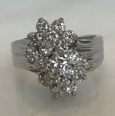 Here is an absolutely beautiful 14k white gold cluster diamond ring. This beauty is set with a total of 17 diamonds. These bright white diamonds will be causing a lot of attention! Materials: 14K White gold Stone: 1- RB .15cttw, 16- RB .80cttw Size: 8 Weight: 7.6 grams Sku: 21SB092318EVZ If you have any questions on this item, please message us! GandDJewelers.etsy.com For ring sizing, please contact us for information. Please note that all of our pieces have been analyzed & identified by a G Diamond Cluster Ring In Fine Jewelry Style, Brilliant Cut Cubic Zirconia Cluster Ring, Wedding Cluster Ring Made Of Diamond, Wedding Cluster Ring With Diamonds, Diamond Cluster Ring In White Gold, Cluster Ring With Single Cut Diamonds In Cubic Zirconia, Fine Jewelry Diamond Ring With Single Cut Cluster, Diamond White Cluster Rings, Dazzling Diamond Cluster Ring With Single Cut Diamonds