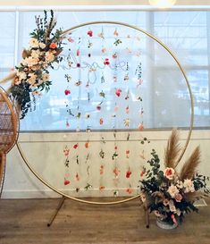 an arrangement of flowers is displayed in front of a large circular display with gold hoop