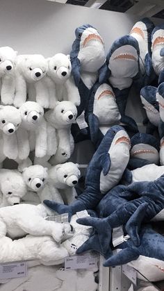 many stuffed animals are on display for sale in a store with shark heads and teeth