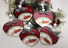 four snowman heart ornaments hanging from a christmas tree