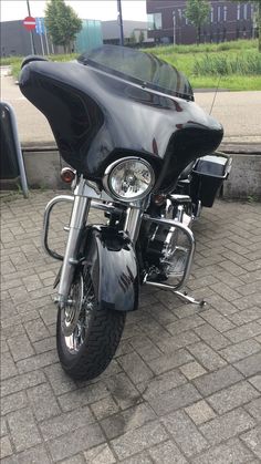 a black motorcycle parked on top of a brick road