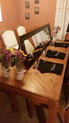 a wooden table topped with lots of vases filled with flowers next to a mirror