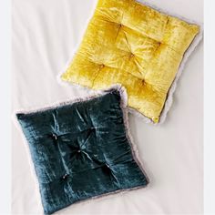 two pillows on a bed with one yellow and the other teal green in color