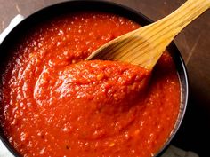 a wooden spoon in a pot filled with red sauce