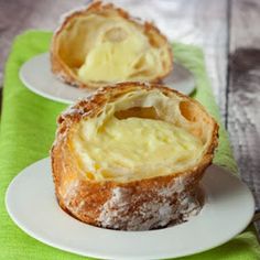 two white plates topped with pastries on top of a green table cloth next to each other