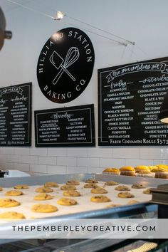 there are many cookies on the counter in front of the bakery's menus