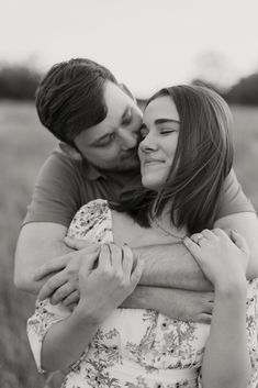 a man and woman hugging each other in a field